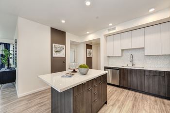 Model home kitchen with dark cabinets on the bottom and white cabinets towards the top.  Stainless steel dishwasher and pull-out kitchen faucet